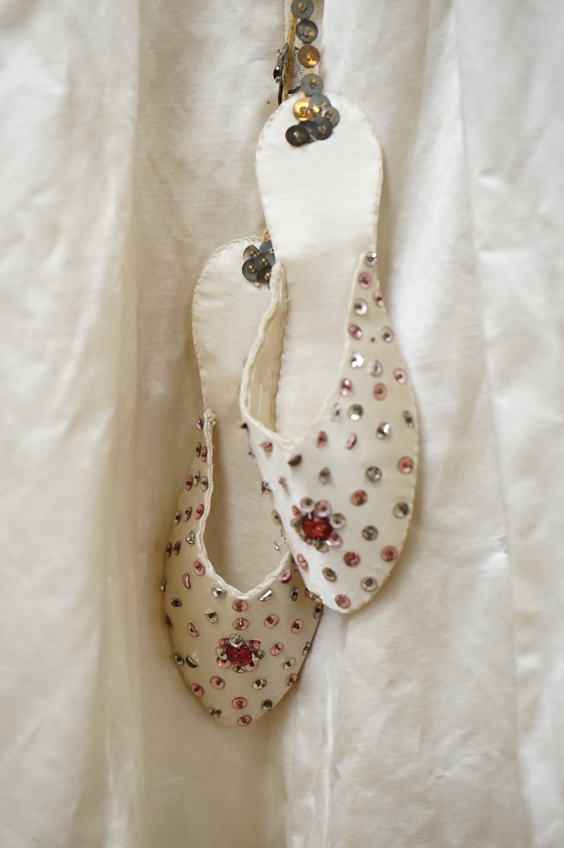 A cream silk satin theatrical costume, mounted with sequined braiding and pair of novelty shoes. Bust measurement 30inches.